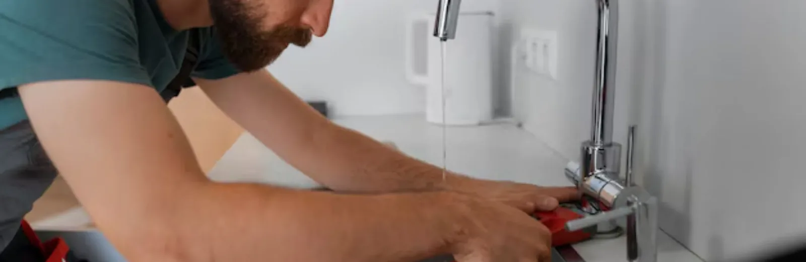 Plumber working on a kitchen faucet and sink plumbing
